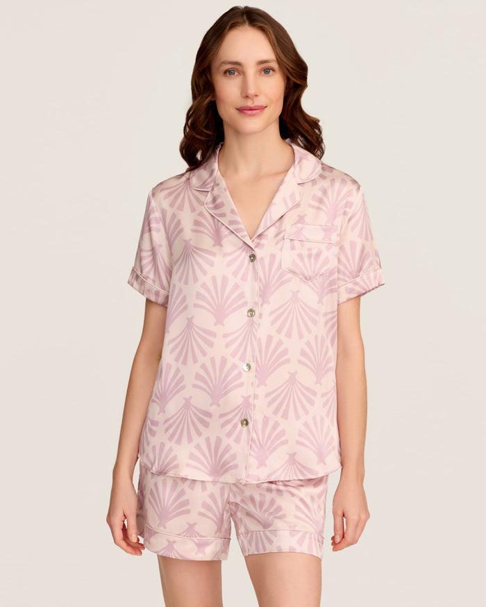 The Women's Silk Short Sleeve Short Set in Blush Tide features a matching pink button-up top and elastic-waist shorts, both adorned with a light purple geometric fan pattern.