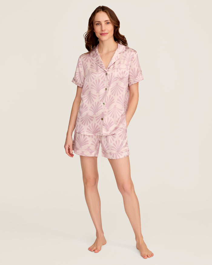 The Women's Silk Short Sleeve Short Set in Blush Tide features a matching pink button-up top and elastic-waist shorts, both adorned with a light purple geometric fan pattern.
