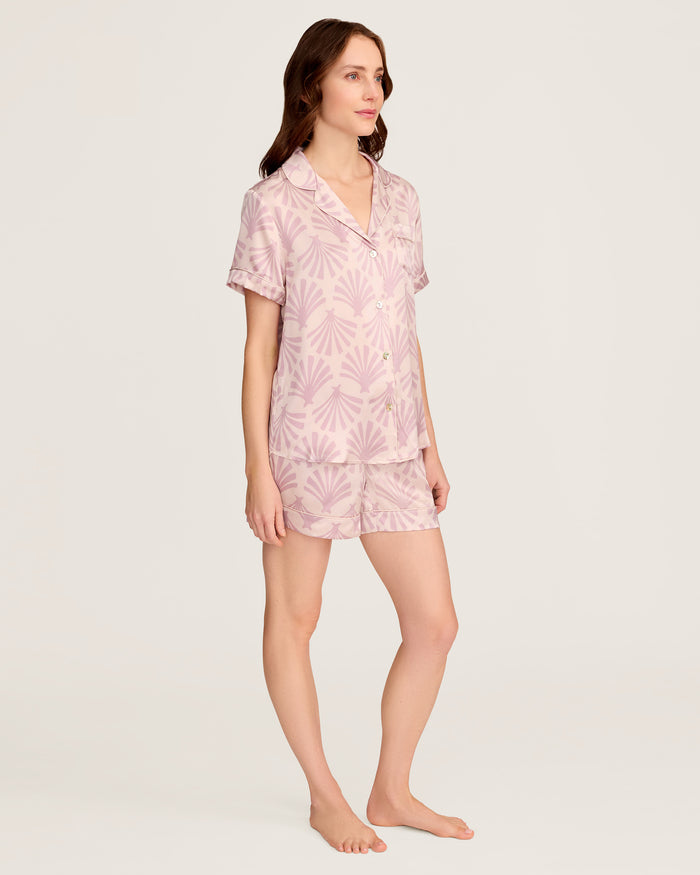 The Women's Silk Short Sleeve Short Set in Blush Tide features a matching pink button-up top and elastic-waist shorts, both adorned with a light purple geometric fan pattern.