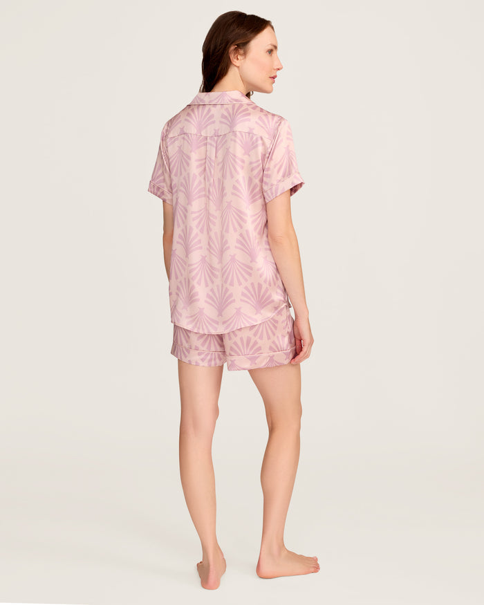 The Women's Silk Short Sleeve Short Set in Blush Tide features a matching pink button-up top and elastic-waist shorts, both adorned with a light purple geometric fan pattern.