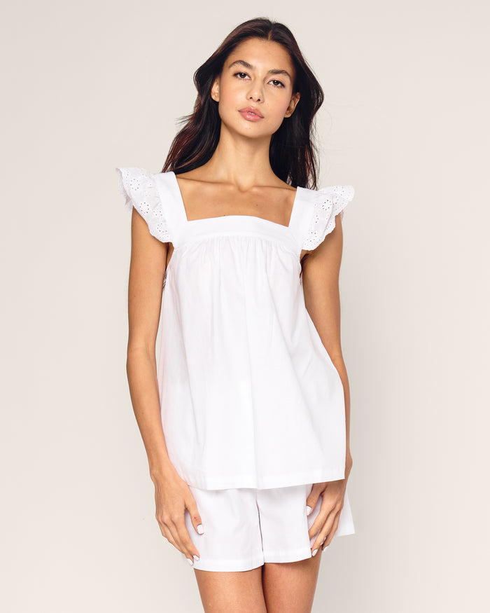 A woman with long dark hair wears the Petite Plume Womens Twill Clara Short Set in White, a luxurious cotton sleepwear. She stands against a neutral background, gazing calmly at the camera.