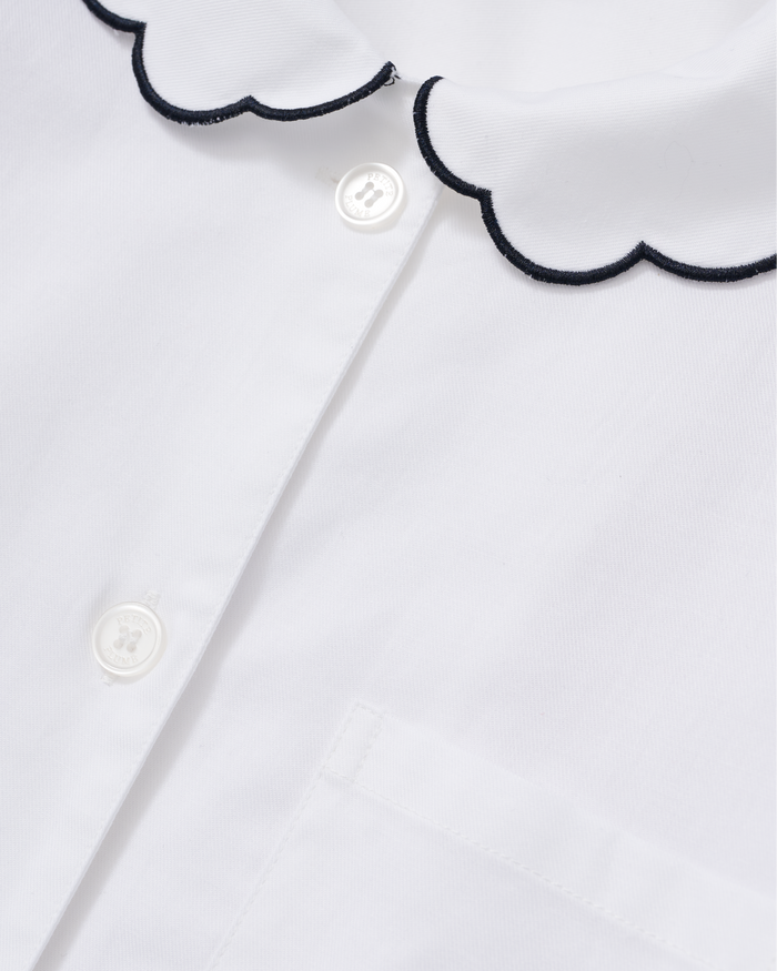 Close-up of the Women’s Twill Colette Pajama Set in White with Navy Piping, featuring white buttons, a front pocket, and a scalloped collar trimmed with navy piping.