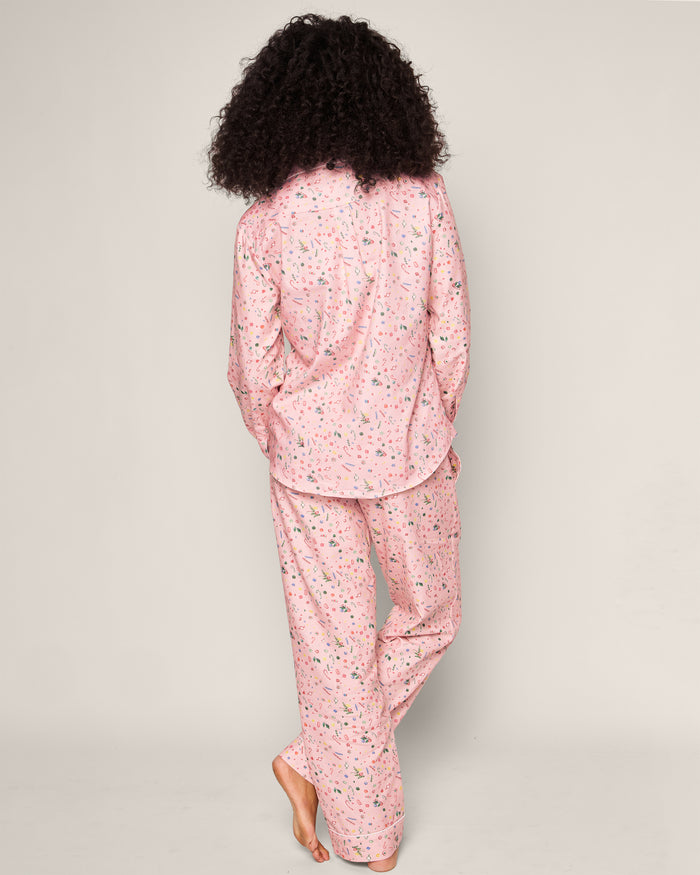 A barefoot person with curly hair poses against a plain backdrop, wearing Petite Plumes Womens Twill Pajama Set in Vintage Sweets, featuring nostalgic floral pink pajamas.