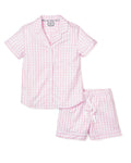 The Womens Twill Pajama Short Set in Pink Gingham by Petite Plume is a luxurious two-piece set with a soft cotton top featuring buttons and a chest pocket, paired with shorts that have an elastic waistband and white drawstring for comfort.