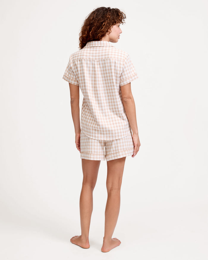 The Women's Twill Short Sleeve Short Set in Camel Gingham features a button-up shirt and matching drawstring shorts with a beige and white gingham pattern.