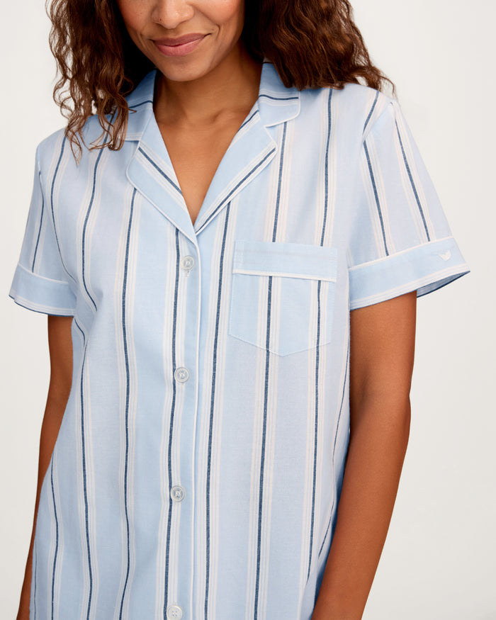 A woman is wearing the Women’s Twill Short Sleeve Short Set in Coastal Stripe, standing against a plain background and smiling.