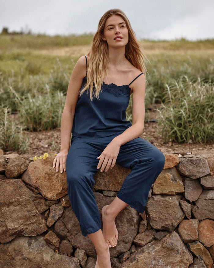 A woman stands barefoot against a plain light background, wearing the Women's Voile Fleur Cami Pant Set in Navy.