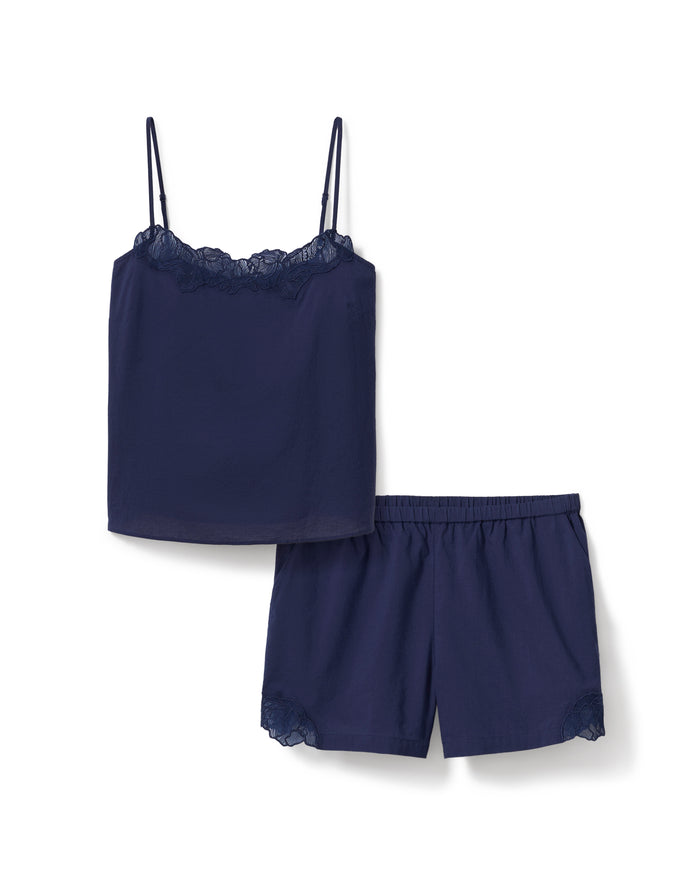 A woman stands barefoot against a plain background, wearing the Women's Voile Fleur Cami Short Set in Navy. She has wavy hair and her hands are in her pockets.