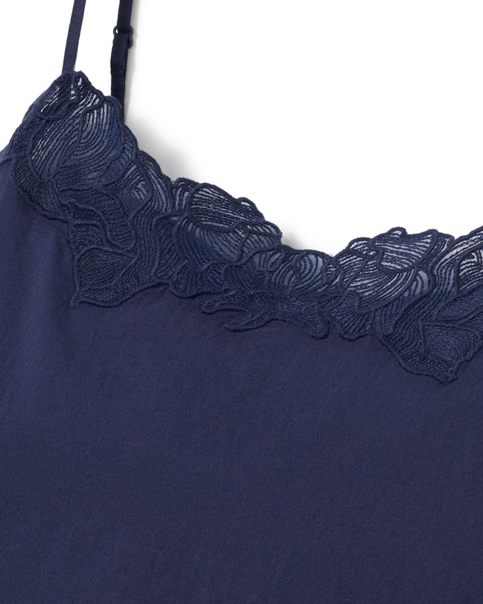 A woman stands barefoot against a plain background, wearing the Women's Voile Fleur Cami Short Set in Navy. She has wavy hair and her hands are in her pockets.