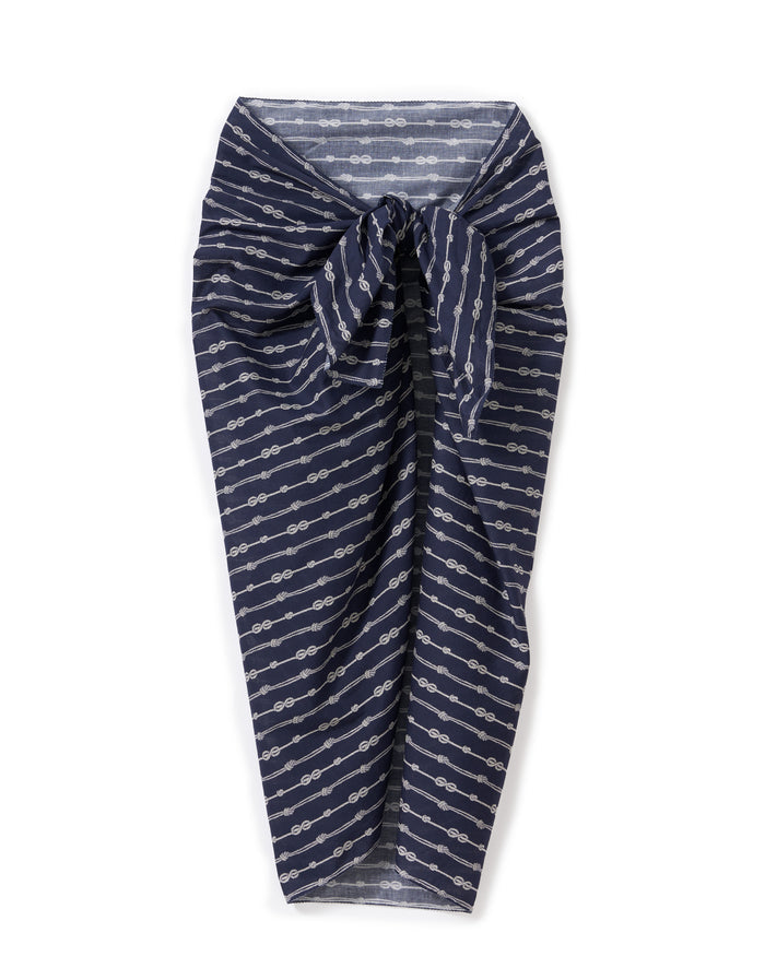 The Women’s Voile Pareo in Nautical Knots, featuring white geometric patterns on navy blue fabric and tied in a knot at the front, is displayed against a white background.